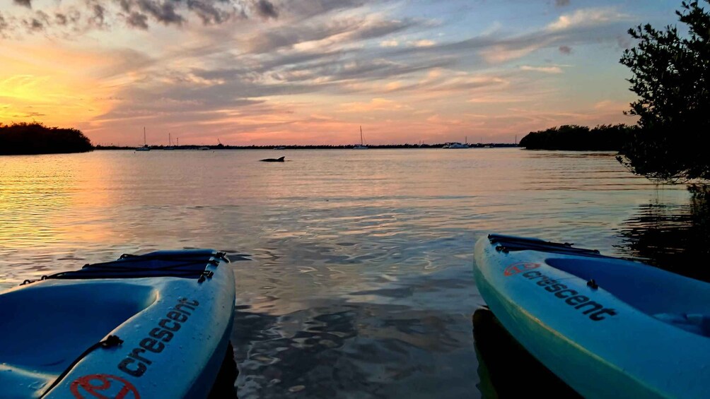 Two canoes labeled 'crescent' docked at a pier with a sunset over a calm body of water. 3