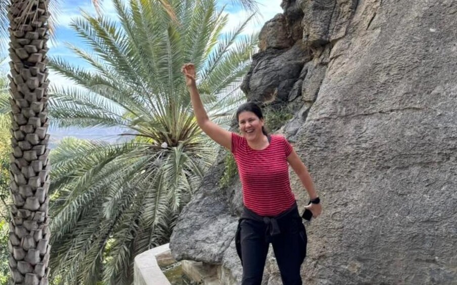A person standing on a rocky path with palm trees in the background. 5