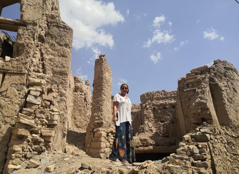 A person standing in front of ancient ruins with stone walls and a clear sky. 3