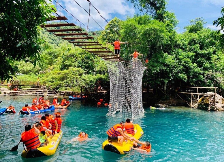 People rafting on a river surrounded by lush greenery and a rope bridge. 5