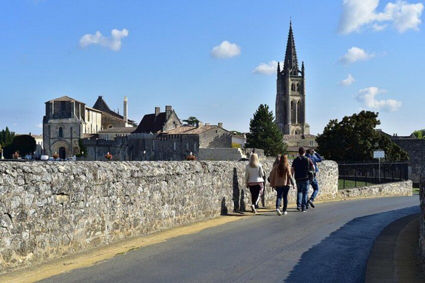 A stone wall, a road, and a tall church tower. 1