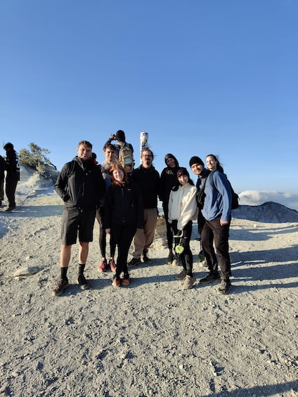 A group of people on a rocky mountain terrain with sparse vegetation and a clear sky. 2
