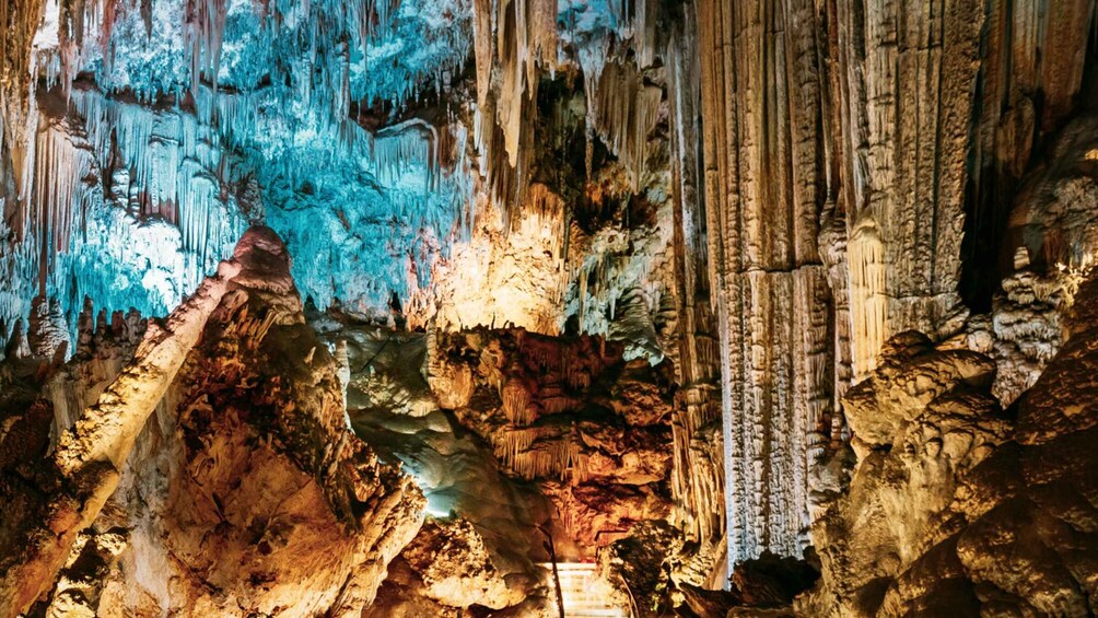 A cave with stalactites and stalagmites, illuminated by artificial lighting. 1