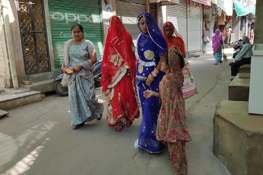 A group of women in traditional attire walking on a street. 1