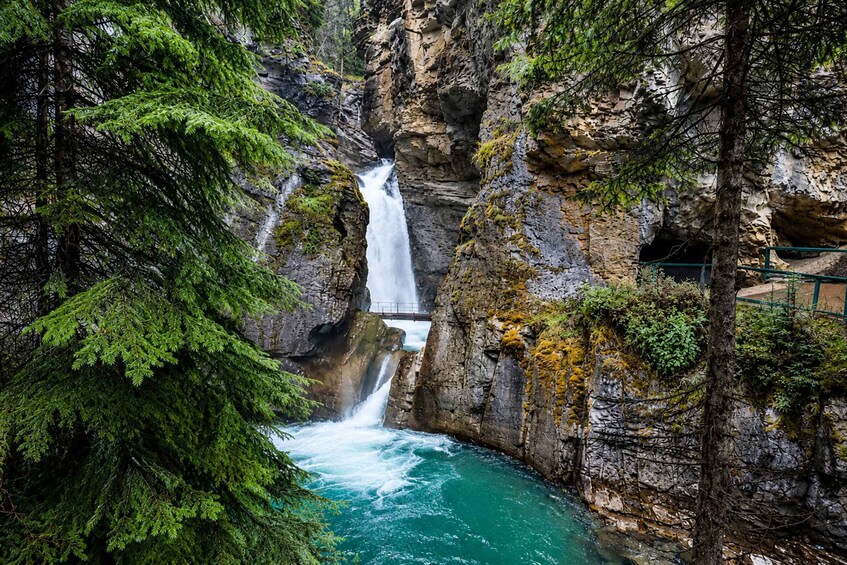 A waterfall cascading into a turquoise pool surrounded by rocky cliffs and dense green foliage. 4