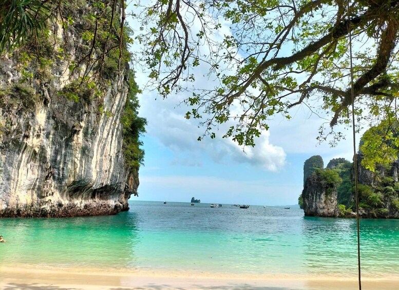 A coastal landscape with clear turquoise waters, rocky cliffs, and a sandy beach. 1
