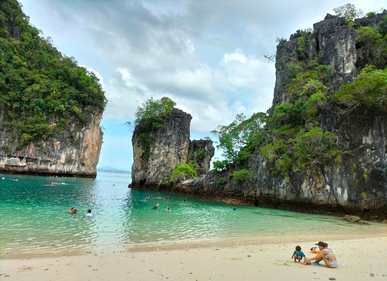 A beach with clear turquoise water, surrounded by rocky cliffs and lush greenery. 5