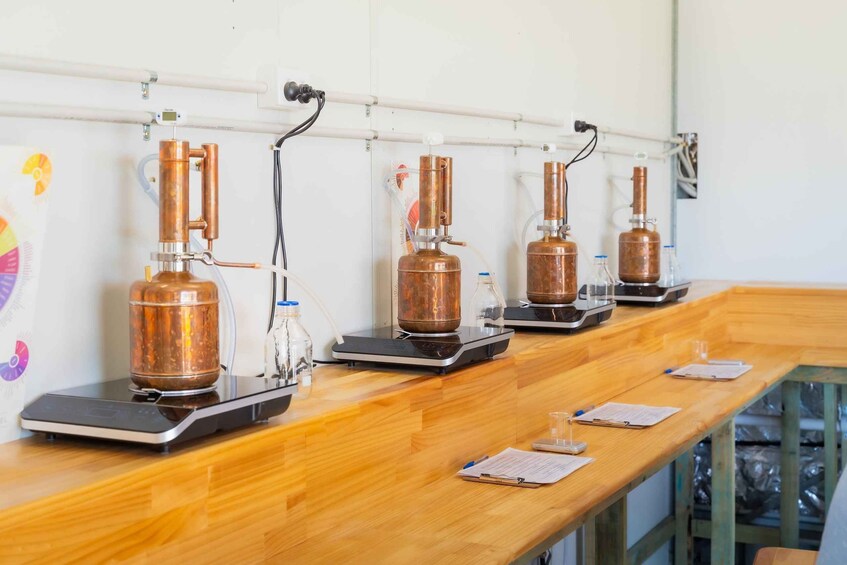 A laboratory setup with copper distillation apparatuses on a wooden bench. 1