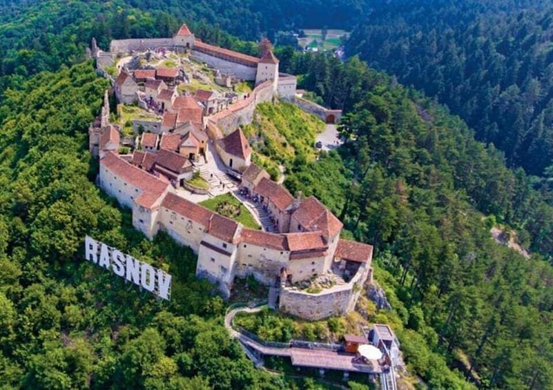 A medieval castle surrounded by forested hills. 4