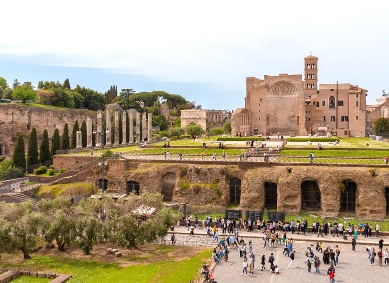 Ancient ruins with columns, a large building with a tower, and a crowd of people. 3