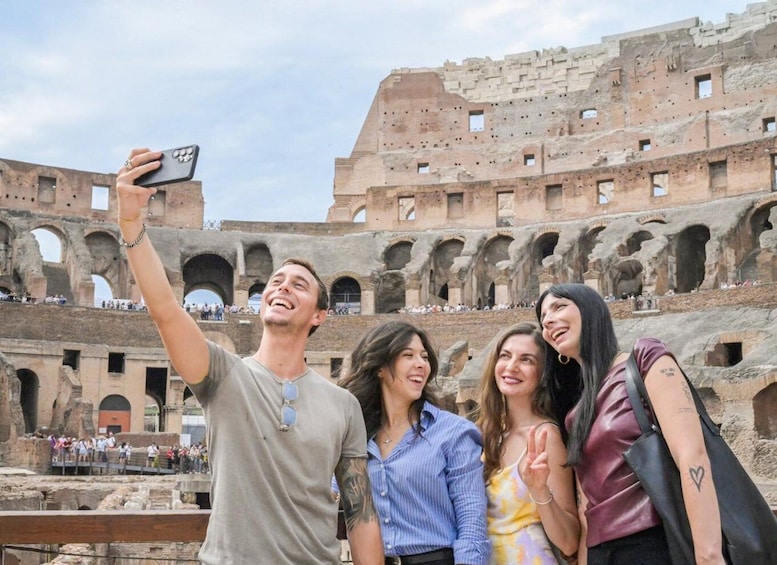 A group of people taking a selfie in front of the Colosseum with its arches and ruins visible. 5