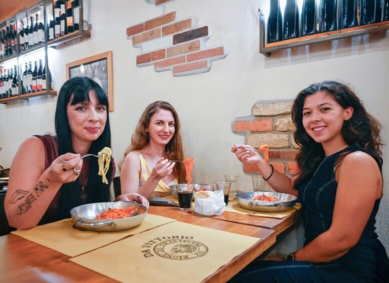Three people dining at a restaurant with a brick wall and wine bottles in the background. 5