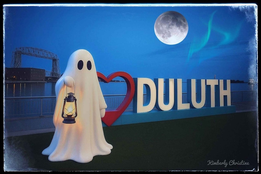 A ghost figure holding a lantern in front of a sign with 'DULUTH' and a heart symbol. 1