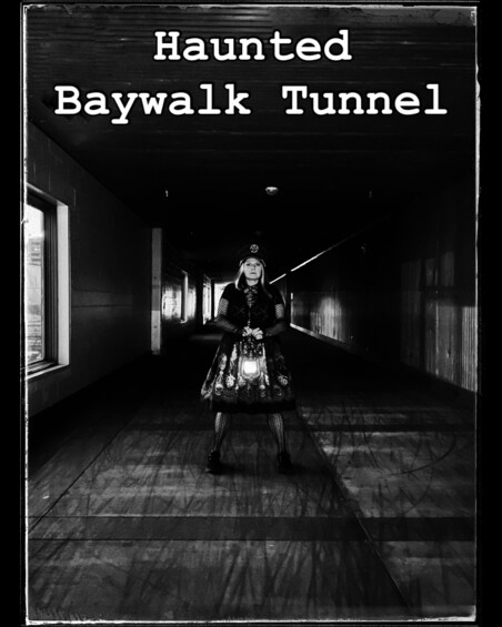 A person in a dark, long hallway with a sign reading 'Haunted Baywalk Tunnel.' 2