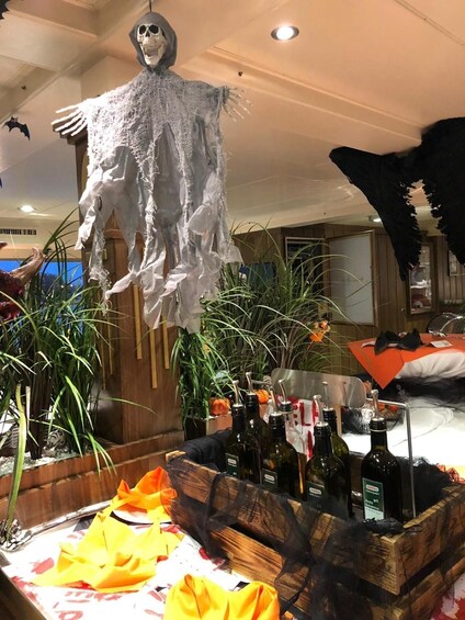 Decoración de Halloween con una figura de esqueleto y una mesa con botellas y una calabaza. 4