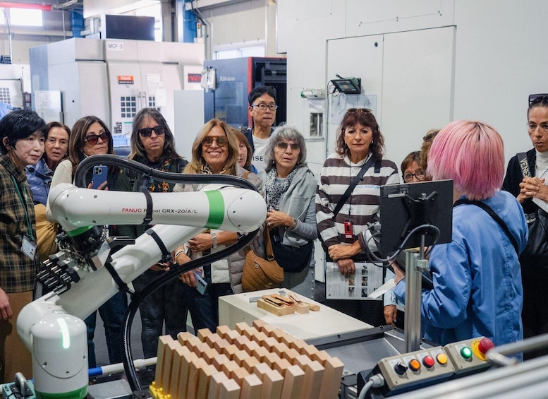A group of people observing a FANUC robot in a laboratory setting. 1