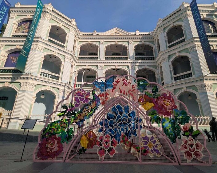A building with classical architecture and a colorful pixelated floral installation in front. 5