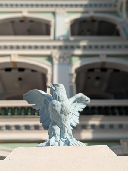 A statue of an eagle with outstretched wings in front of a building with arched windows. 3