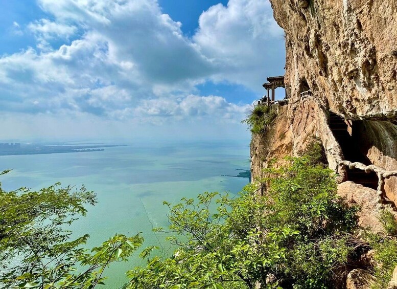 A cliff with a temple on top overlooking a calm sea. 2