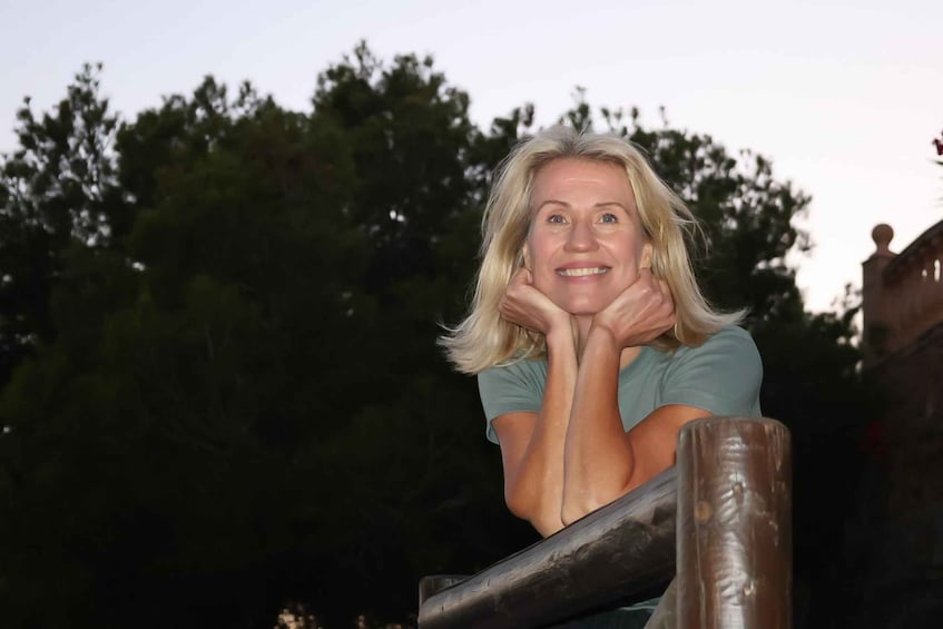 A person leaning on a wooden structure with trees in the background. 1