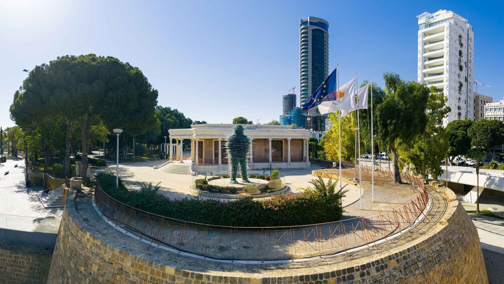 A public square with a fountain, a statue, and modern buildings in the background. 2