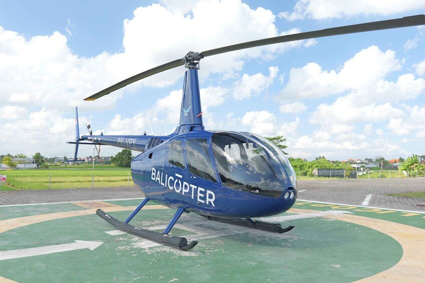 A blue helicopter with 'BALICOPTER' written on its side parked on a helipad. 2
