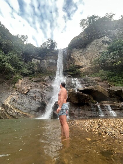 Un uomo in piedi in acque basse, davanti a una cascata. 2