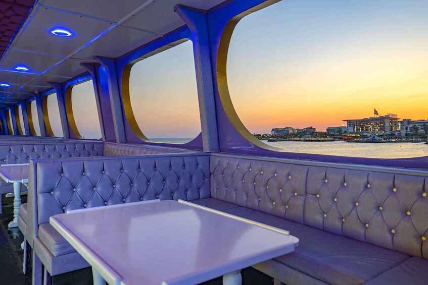 A row of purple upholstered benches and tables on a cruise ship deck, with a view of the sunset over the water. 5