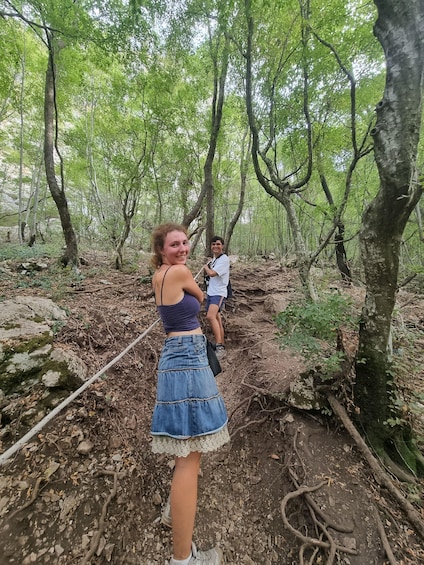 A forest with a woman in a denim skirt and a man in a white shirt. 2