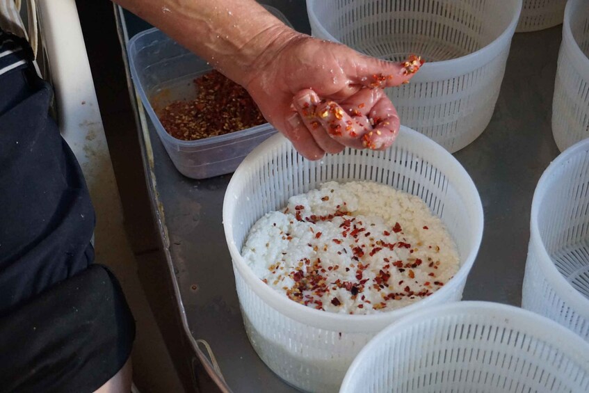 A person seasoning white rice with red spices in a kitchen setting. 3