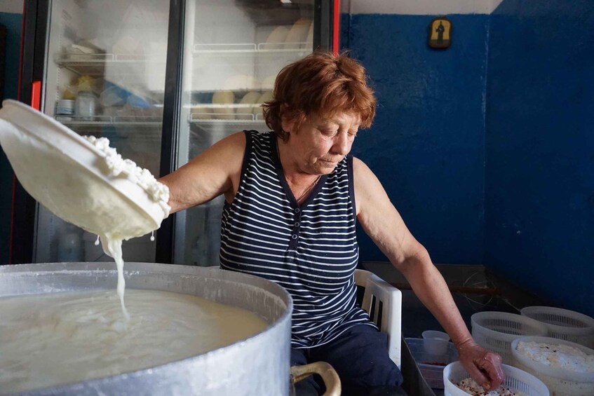 A person pouring a thick liquid from a ladle into a large pot. 5
