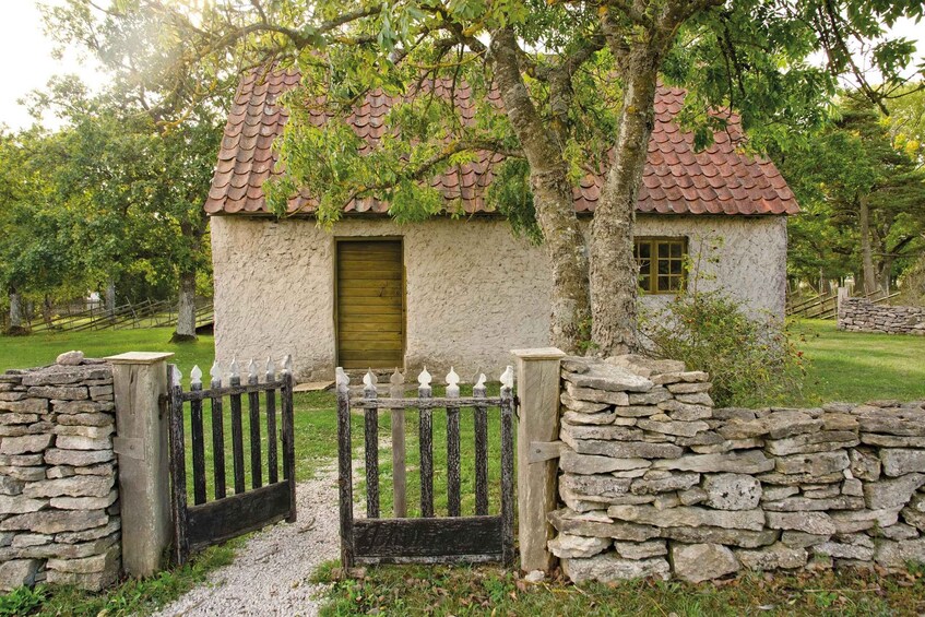 A rustic stone house with a tiled roof, a wooden gate, and a stone wall. 5
