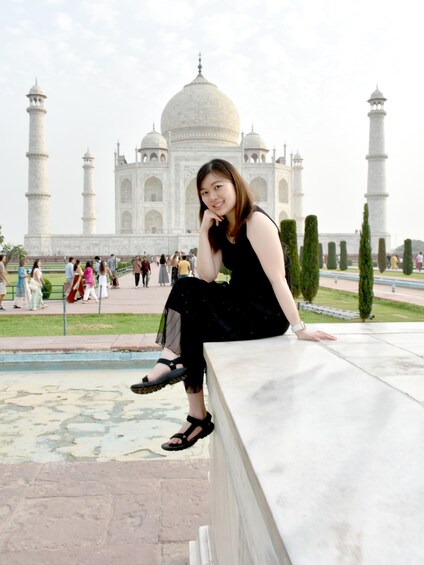 A person sitting on a marble ledge with the Taj Mahal in the background. 3