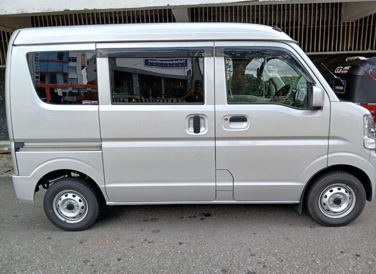 A silver van parked on a street with a building in the background. 2