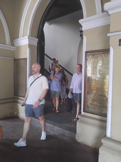 A group of people ascending a staircase in a building with arched doorways and a framed historical plaque. 5