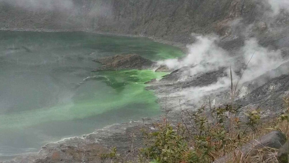 A geothermal area with green water and steam. 1