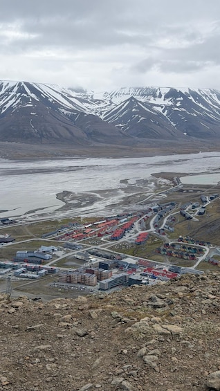 A town with buildings and a river, surrounded by snow-capped mountains. 5