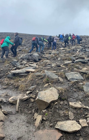 A group of hikers navigating a rocky terrain with large boulders and sparse vegetation. 2