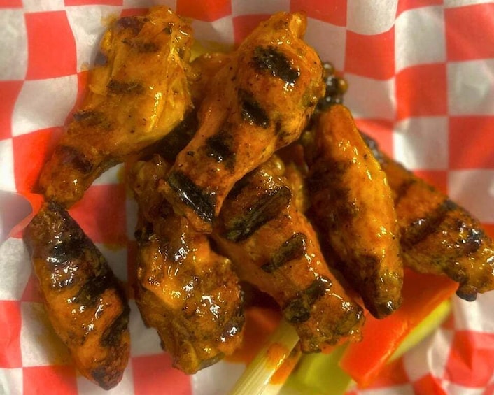 Grilled chicken wings on a red and white checkered paper. 5