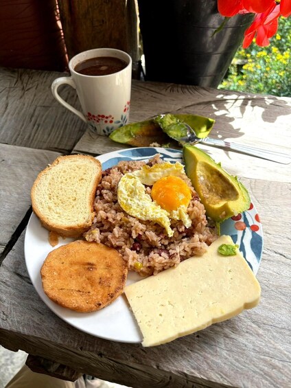 A plate of food with rice, an egg, avocado, toast, and a biscuit on a table. 2