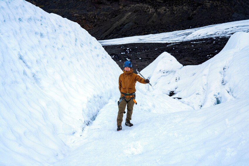 Une personne se tient dans un paysage enneigé, avec un terrain recouvert de neige et un arrière-plan rocheux. 2