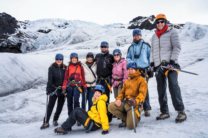 Un groupe de personnes, vêtues pour l’hiver, se trouve sur une montagne enneigée, avec un glacier en arrière-plan. 3
