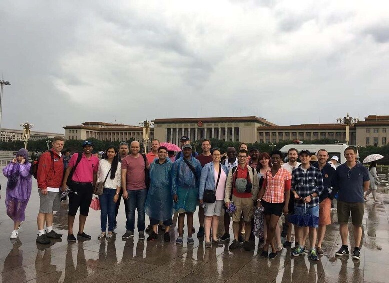 A group of people standing in a wet outdoor area with a large building in the background. 3
