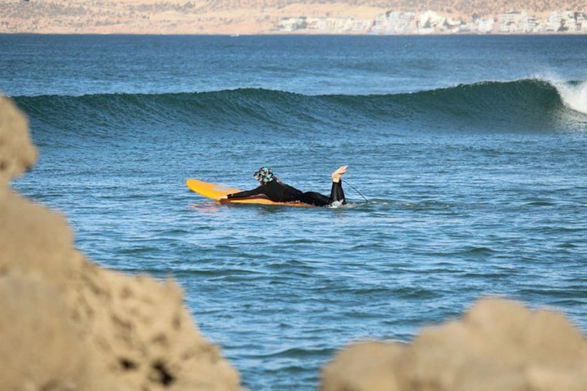Un surfeur allongé sur une planche de surf dans l’océan, avec des vagues. 1