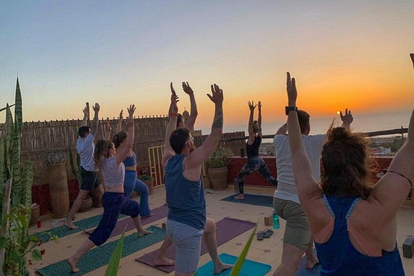 Un groupe de personnes pratiquant le yoga en plein air, avec un coucher de soleil en arrière-plan. 5