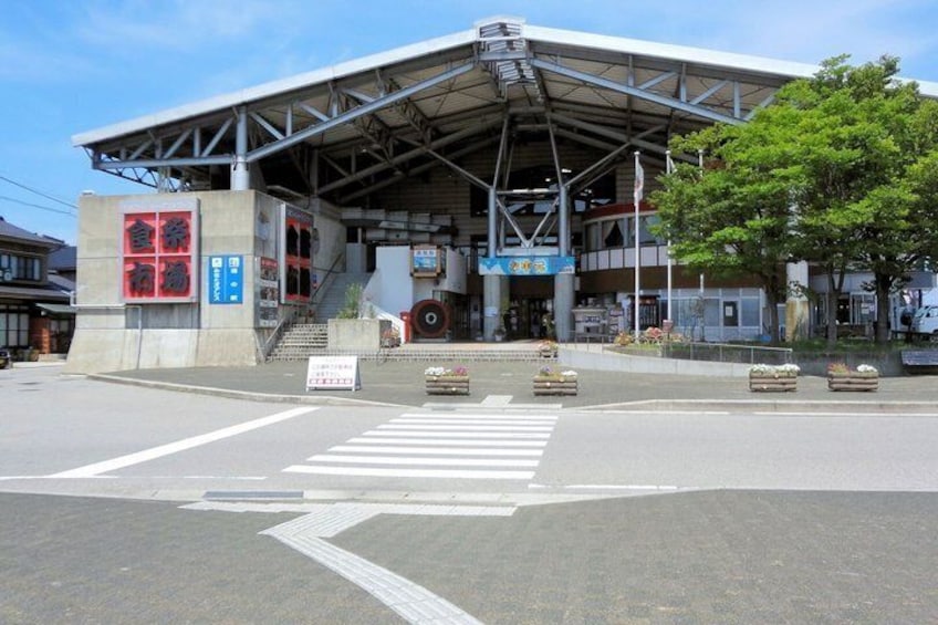 A train station with a covered platform, a pedestrian crossing, and a signboard. 3