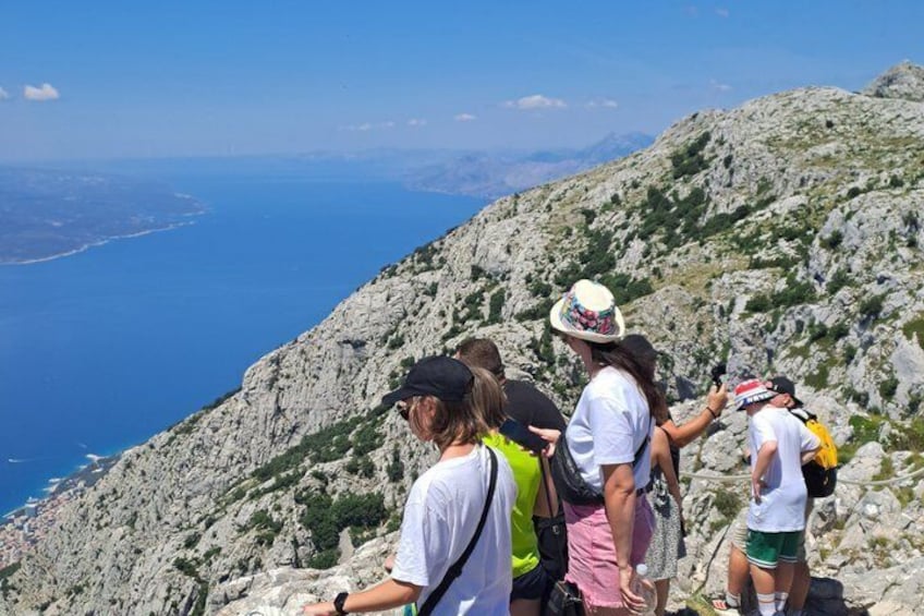 A group of hikers on a mountainous trail with a view of the sea. 2