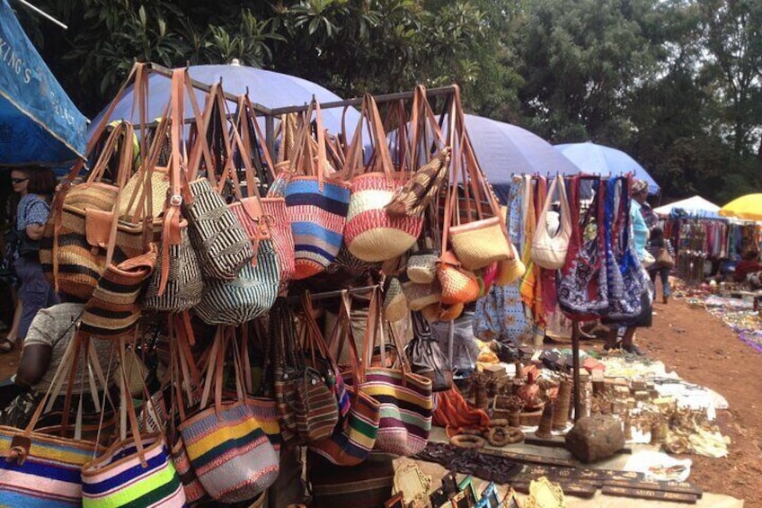 Un mercato con colorate borse tessute e tessuti esposti sotto gli ombrelli. 3