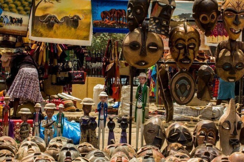 Una bancarella di mercato con diverse maschere e sculture in legno. 5