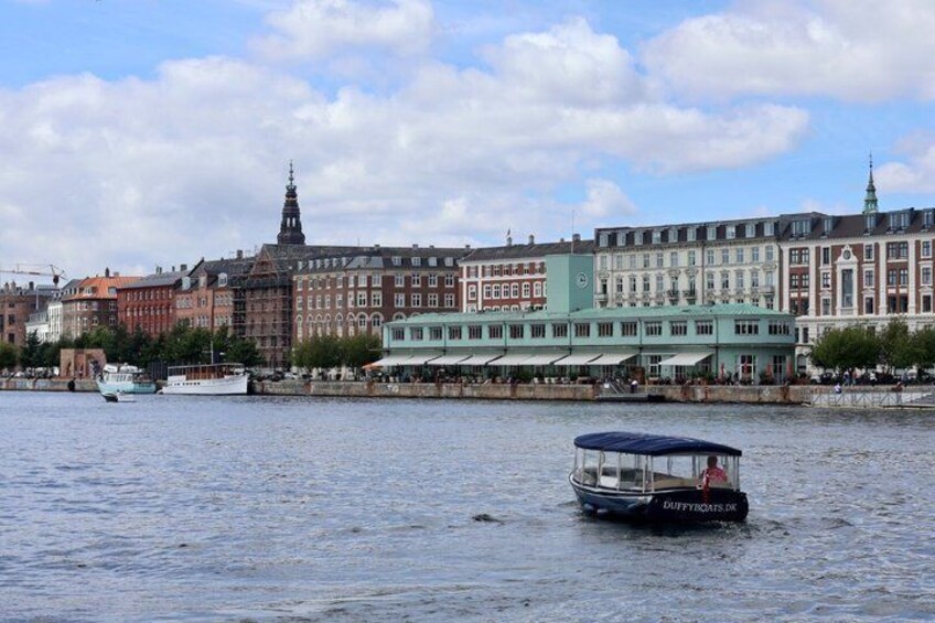 A river with boats, historic buildings, and a prominent church spire. 2